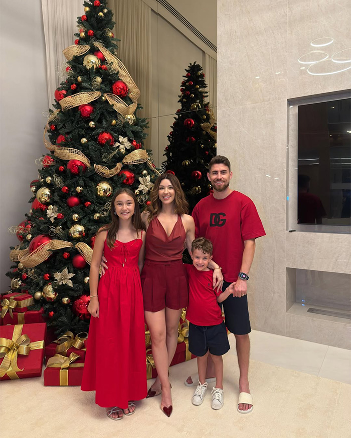 Family posing in red outfits beside a decorated Christmas tree, related to Chappell Roan and Jude Law's daughter backlash. Family posing in red outfits beside a decorated Christmas tree, related to Chappell Roan and Jude Law's daughter backlash.