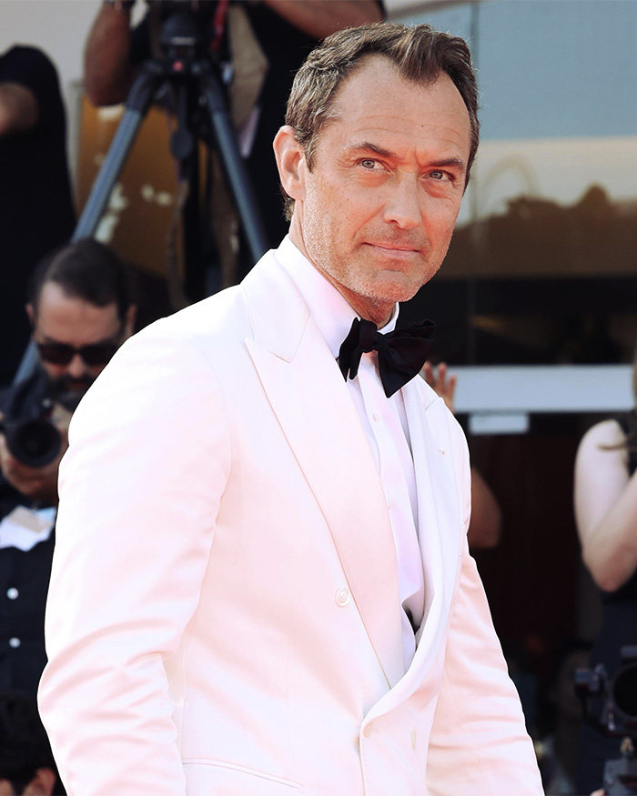 Jude Law in a white tuxedo at a red carpet event amid backlash for treatment of his daughter and security incident. Jude Law in a white tuxedo at a red carpet event amid backlash for treatment of his daughter and security incident.