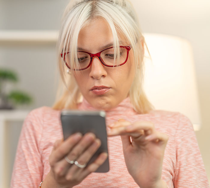 Woman with red glasses using smartphone, reacting to texts about woman sleeping with married man and giving a lecture.
