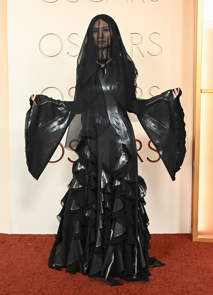 Person in a dramatic black ruffled gown and veil at the Oscars, showcasing most outrageous and disastrous looks from the event.