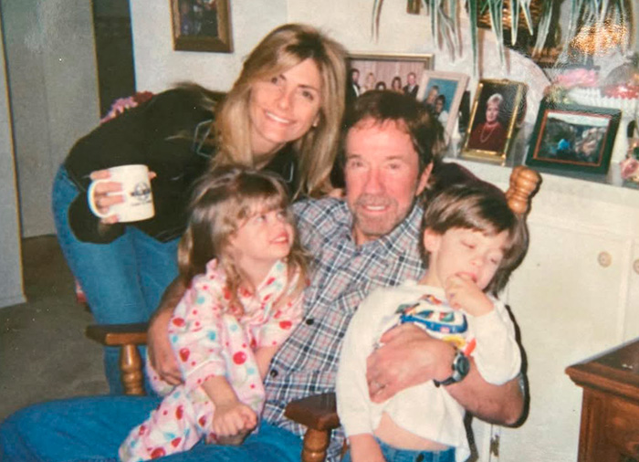 Chuck Norris com seus filhos sorrindo em casa, capturando um momento familiar antes de sua notícia repentina.