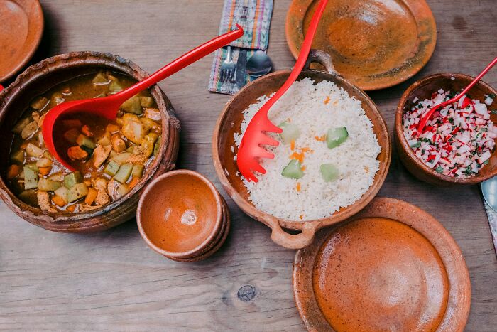 Traditional cultural dishes served in clay pots with rice, stew, and salad showcasing cultural things people thought normal.