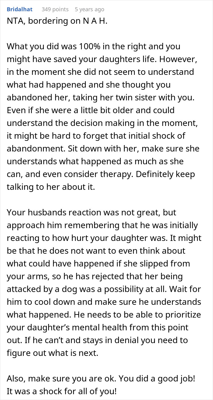 Wife holding twin girls near a fence while being chased by a dog in an outdoor residential area.