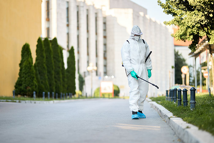 Person in protective suit spraying chemicals outdoors representing corruption in businesses often unnoticed by people.