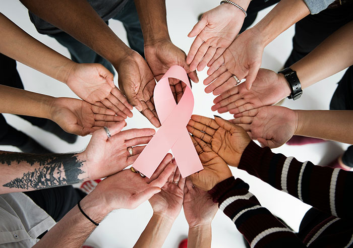 Diverse group of hands surrounding a pink ribbon symbolizing awareness, highlighting corruption in various businesses concept.