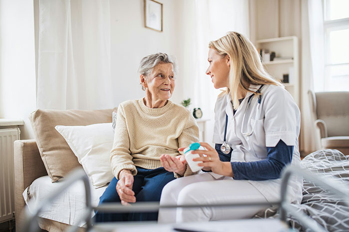 Elderly woman talking with healthcare worker in home setting, highlighting businesses often more corrupt than people know