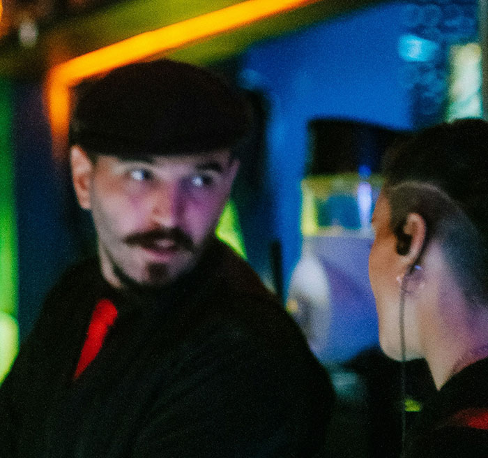 Two coworkers having a tense conversation in a dimly lit workspace, highlighting revenge among coworkers.