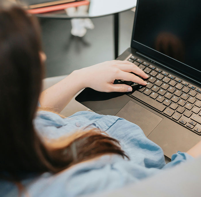 Person working on a laptop at a table, illustrating themes of revenge to coworkers in a casual office setting.