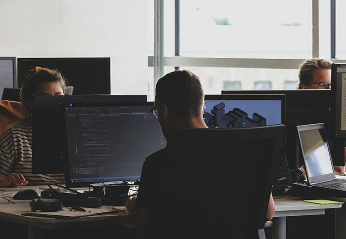 People working at computers in a dark office, highlighting displays of intelligence and focused problem-solving skills.