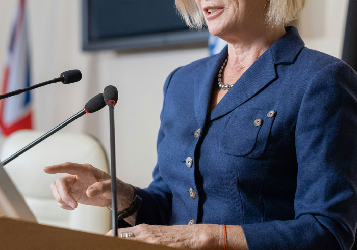 Woman speaking at a podium with microphones, illustrating creepy displays of intelligence seen in others.