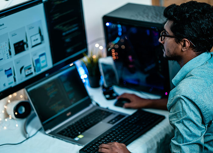 Person wearing glasses working on multiple screens, showcasing a creepy display of intelligence in a tech setup.