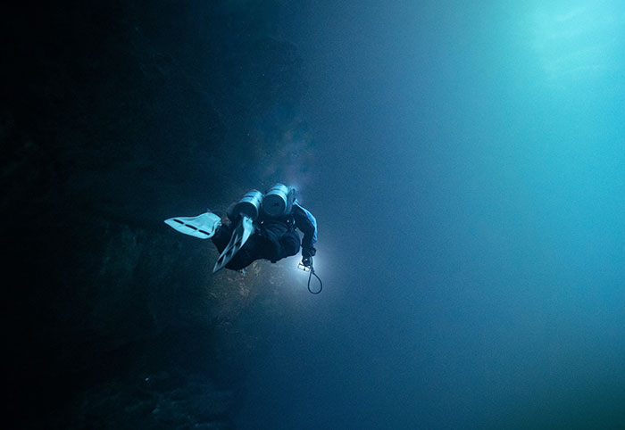 Scuba diver exploring deep dark ocean, highlighting creepy facts about the ocean’s mysterious depths and creatures.