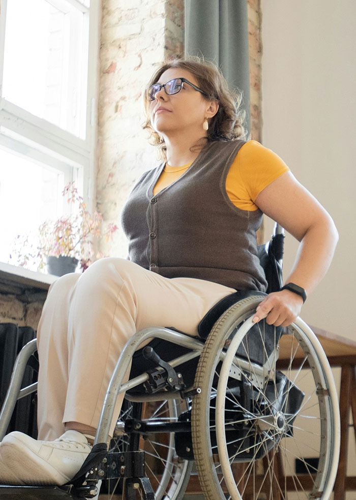 Woman in a wheelchair wearing glasses and casual clothes, illustrating stories of women dealing with men hitting on them creepily.