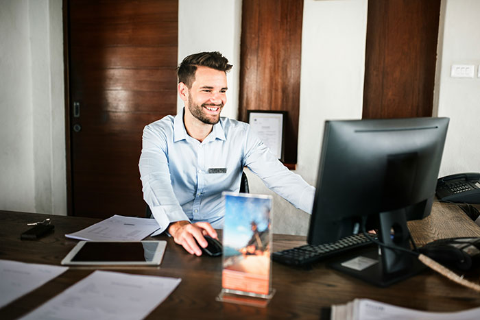 Smiling man working at a desk with computer, representing men hitting on women like absolute creeps in unsettling stories.