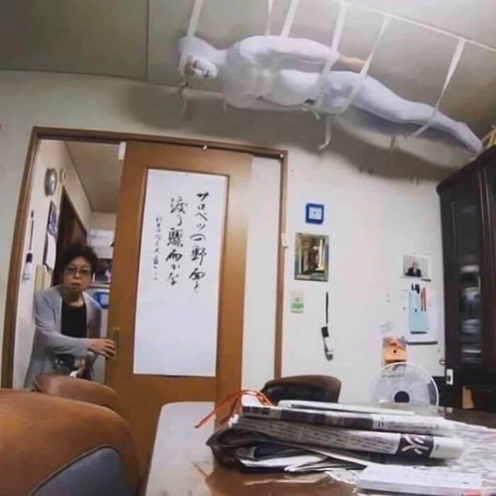 A strange white figure wrapped in cloth is suspended from the ceiling, creating a weird and cringey photo scene.