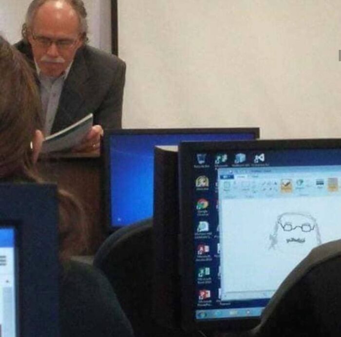 Man resembling drawing on computer screen in a classroom setting, a photo quite difficult to look at for its weird and cringey vibe