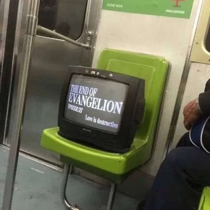 Old TV placed on a green subway seat showing a screen with text, a weird and cringey photo on public transport.
