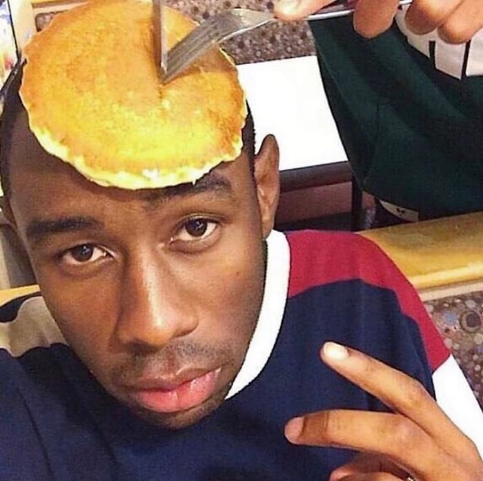 Man with a pancake on his head being cut, one of the weird and cringey photos difficult to look at.
