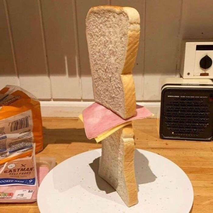 Slices of bread and ham stacked vertically in a weird and cringey arrangement on a kitchen counter.