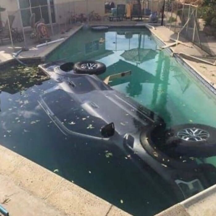 Upside-down car submerged in a backyard pool, a weird and cringey photo difficult to look at.