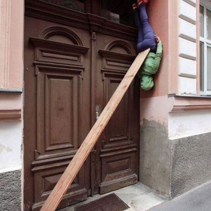 Person stuck upside down on wall supported by wooden plank in a weird and cringey photo difficult to look at.