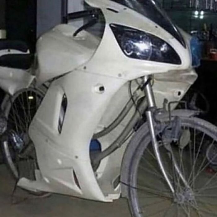 Bicycle modified with white motorcycle fairing, creating a weird and cringey look that is difficult to look at.