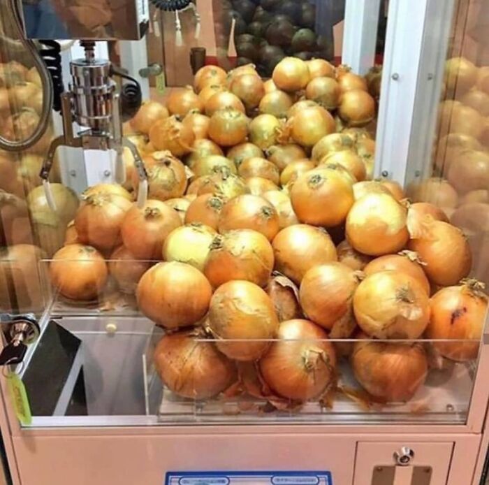 Claw machine filled with onions instead of toys, a weird and cringey photo hard to look at.