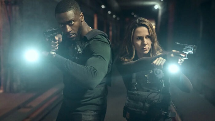 Two armed actors aiming guns with flashlights in a dark alley, representing Prime Video&rsquo;s Cross series renewal.