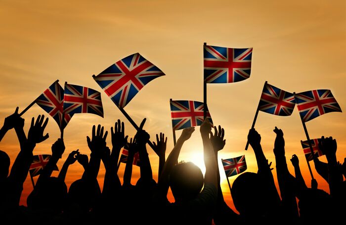 Silhouettes of people holding and waving UK flags at sunset, illustrating vanished truths from home countries in a thread.