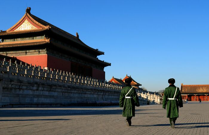 Two guards walking near a historic building, illustrating vanished truths from people's home countries shared online.