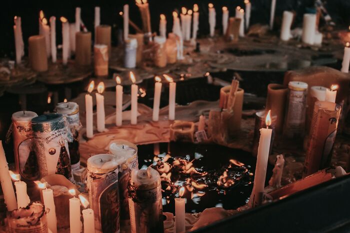 Dimly lit scene with numerous burning candles creating an eerie atmosphere for urban explorers.