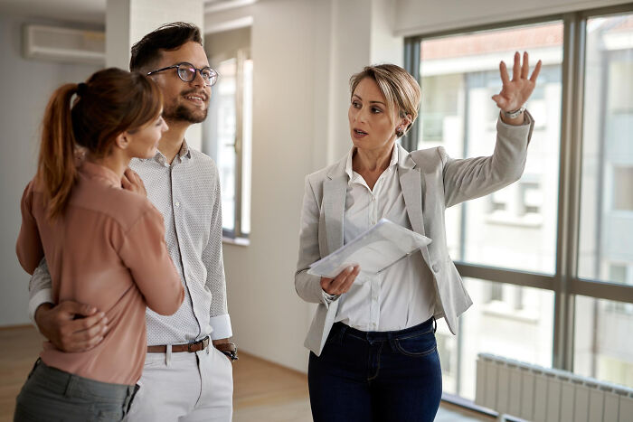 Businesswoman sharing dark industry secrets with a couple during a discussion in a bright modern office setting.