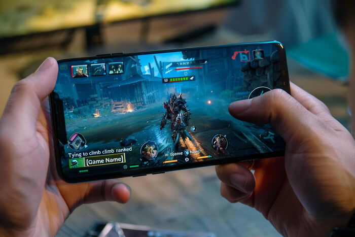 Person holding smartphone playing a dark industry game, revealing dark industry secrets behind the digital facade.