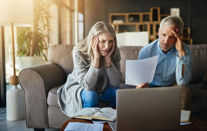 Concerned man and woman reviewing documents and laptop, illustrating dark industry secrets behind the facade.
