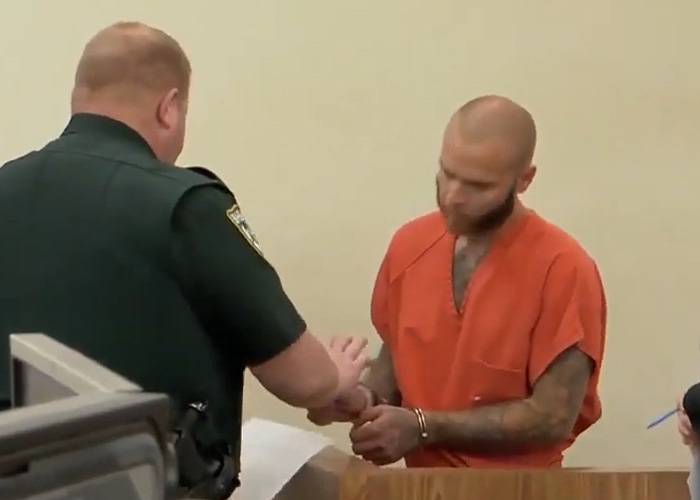 Man in orange prison jumpsuit handcuffed in courtroom, mom allegedly allowing boyfriend to harm young son with injuries case