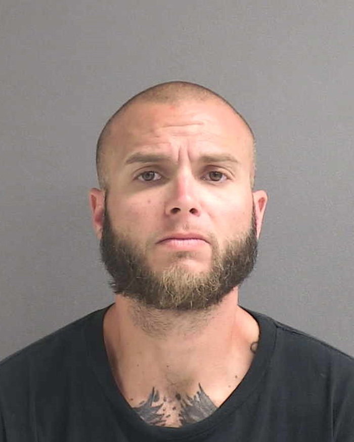 Mugshot of a man with a beard and short hair against a gray background related to harm and injury case.