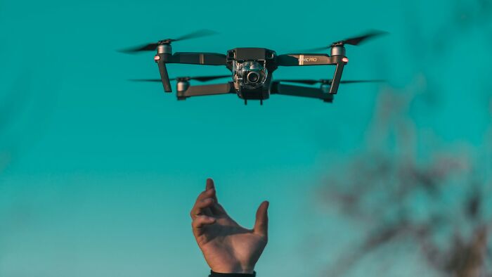 Drone flying above an outstretched hand, capturing a moment that shows payback stories with humor and surprise.