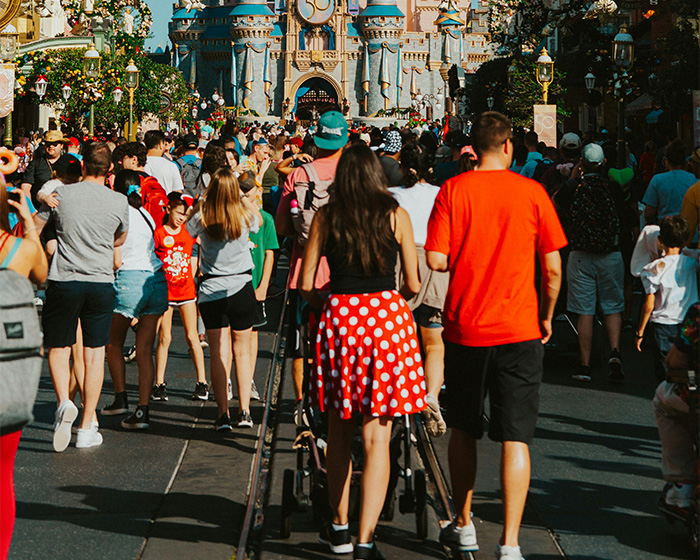 Crowd at Disney World with influencer in polka dot skirt amid discussions of inappropriate outfit complaints and warnings.