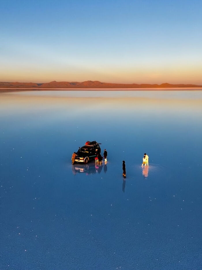 People and a vehicle on a reflective salt flat creating a surreal view that proves reality is incredible and unreal.