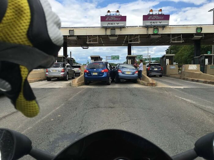 Motorcycle driver approaching a toll booth with cars paying tolls, capturing the essence of travel in the US states.