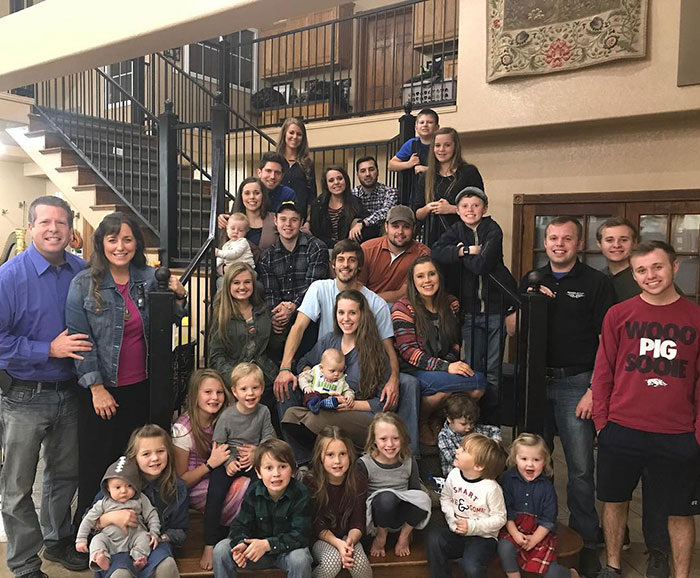Large family group gathered on stairs inside a home, depicting 19 Kids And Counting star Joseph Garrett Duggar and relatives.