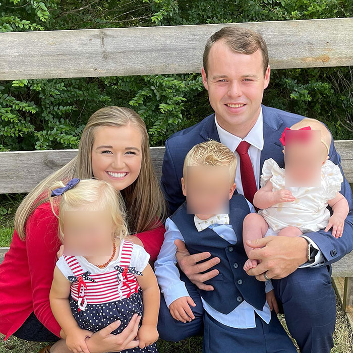 Joseph Garrett Duggar from 19 Kids And Counting posing outdoors with family members on a wooden bench on a sunny day