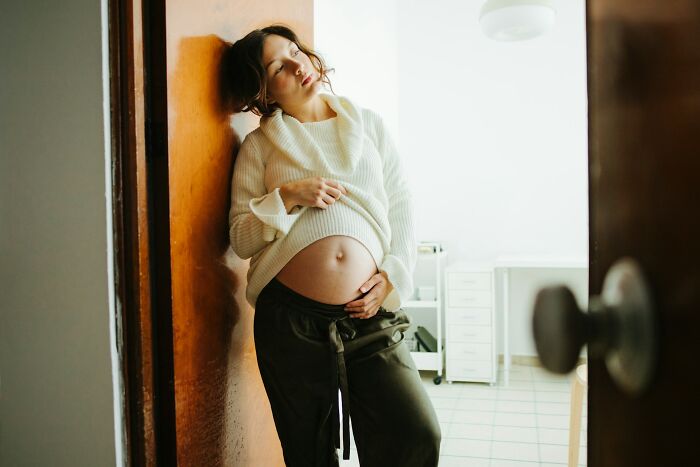 Pregnant woman leaning against a wall looking distressed, illustrating moments people destroyed their own lives instantly.