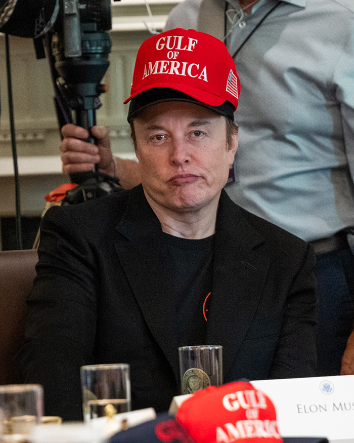 Elon Musk wearing red Gulf of America hat at a public event, unrelated to Paris Fashion Week appearance or estranged daughter debate.