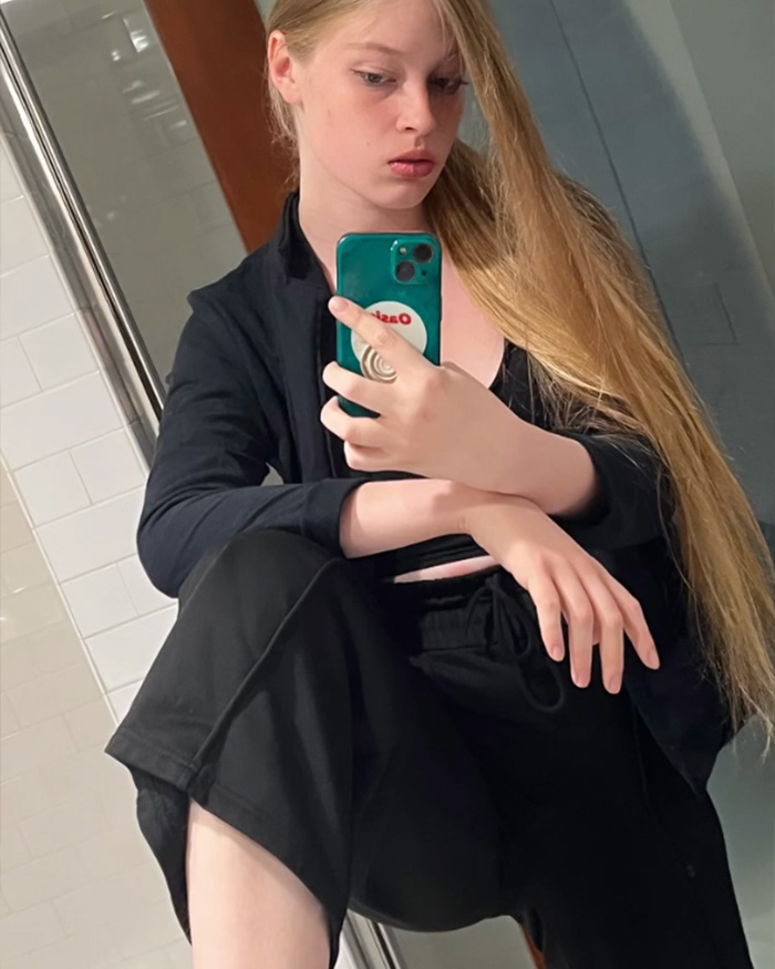 Elon Musk&rsquo;s estranged daughter taking a mirror selfie, showcasing casual black outfit and long blonde hair.