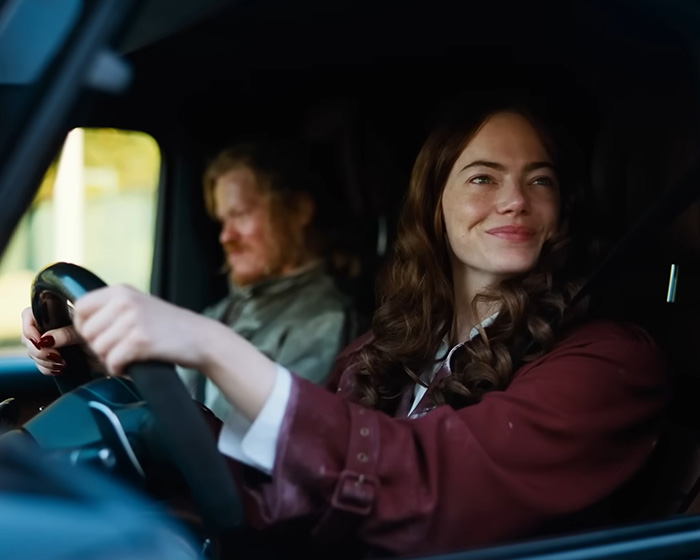 Emma Stone smiling while driving a car, portraying her unexpected appearance at the 2026 Actor Awards event.