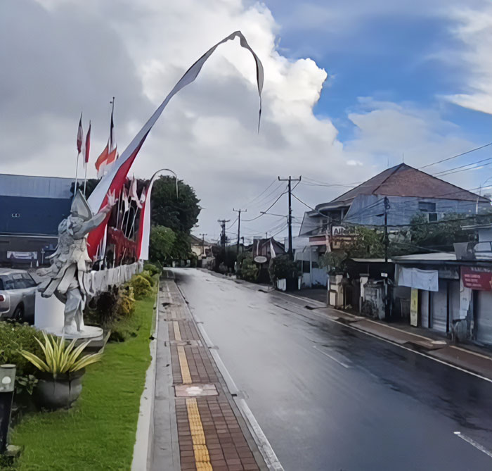 Empty street in Bali during shutdown with statues and flags lining the sidewalk, reflecting consequences for tourists going out in public.