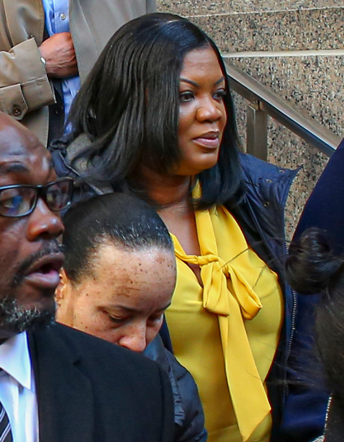 Woman in a yellow blouse among a crowd outside a building, related to Epstein prison guard googling his name before passing.