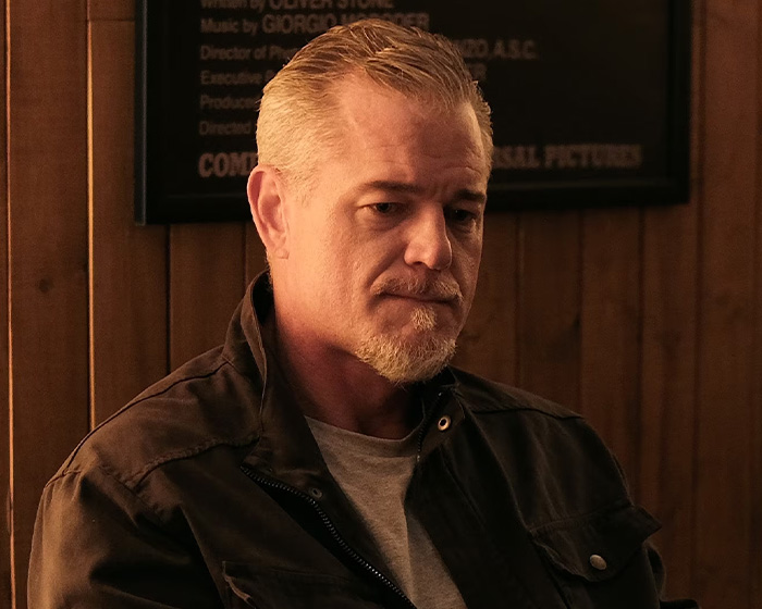 Man with short gray hair and beard wearing a dark jacket sitting indoors with a serious expression related to cause of passing.