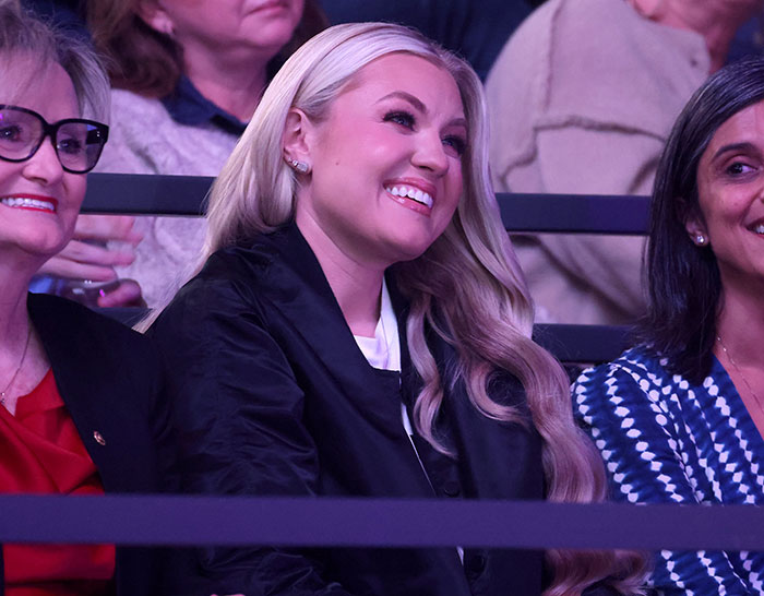 Erika Kirk smiling while seated among an audience, her latest video sparking massive backlash and controversy.